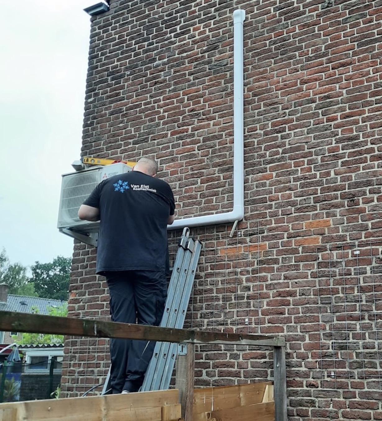 Monteur van Van Elst Koeltechniek bij montage van een buitenunit
